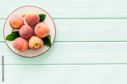 Summer fruits. Ripe red peaches on plate on green wooden table top-down copy space