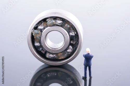 Miniature people : Business man wear blue suit standing in front of ball bearing. Ball bearing place on the other ball bearing. Industrial and business concept