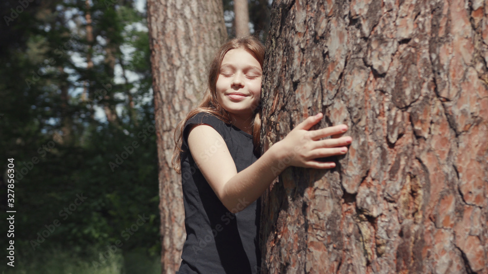 Adorable nature child hugging a tree in the beautiful sunny forest. Portrait of a lovable girl embracing tree trunk caring for the environment. Adorable nature child hugging a tree in the beautiful sunny forest. Portrait of a lovable girl embracing tree trunk caring for the environment.