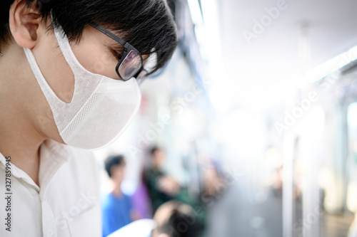Asian man wearing surgical face mask on skytrain or urban train. Wuhan coronavirus (COVID-19) outbreak prevention in public transportation. Health awareness for pandemic protection
