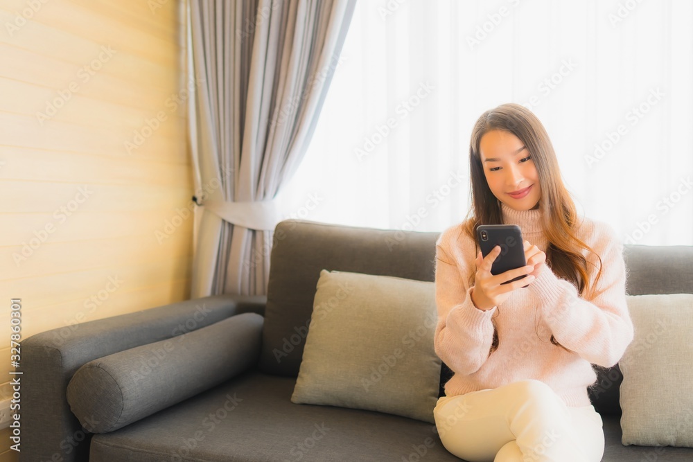 Portrait beautiful young asian woman using smart mobile mobile cellphone on sofa in living room Portrait beautiful young asian woman using smart mobile mobile cellphone on sofa in living room