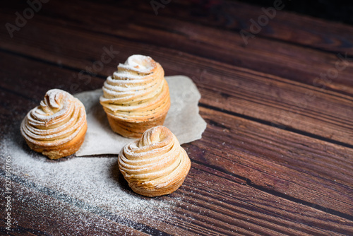 Modern trend baking 2020-cruffins puff muffin , a mixture of croissants and muffins. On a dark wooden table sprinkled with powdered sugar. Place to copy, view from above