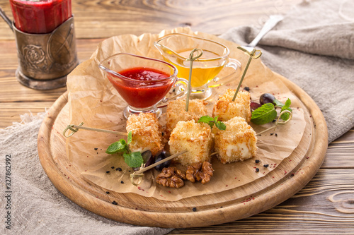 deep fried camembert cheese cubes with cranberry sauce and honey on wooden table
