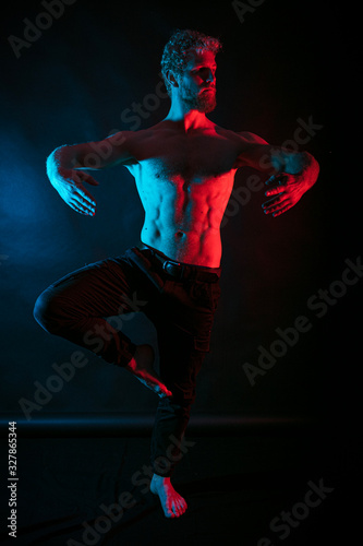 Man dancing ballet. Male wrestler posing. studio black-white background, red and blue lights. © M.V.schiuma