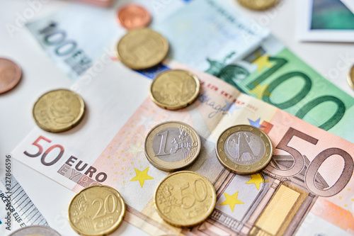 Calculation of expenses. Close up of one euro coin surrounded by different coins and 100 and 50 Euro banknotes