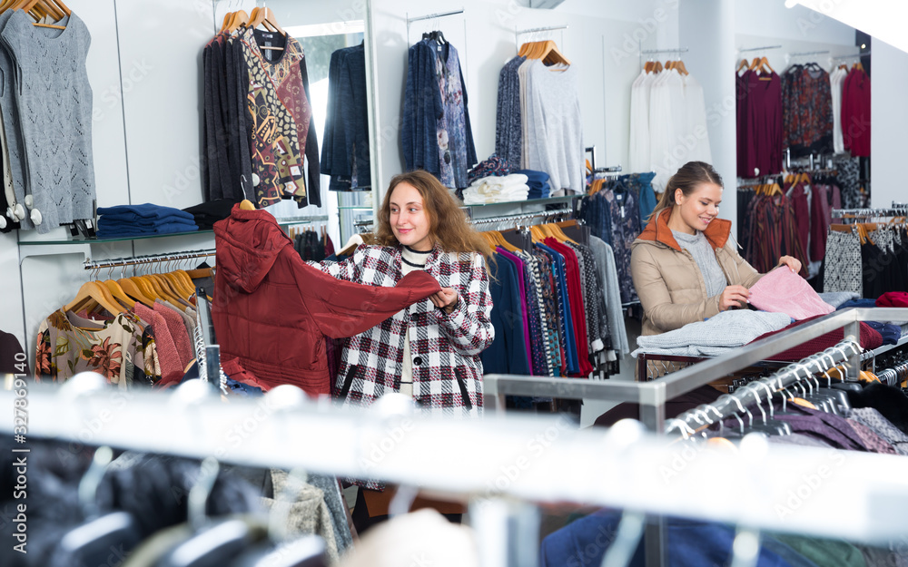 Fototapeta premium Clothing shop with women choosing overcoats