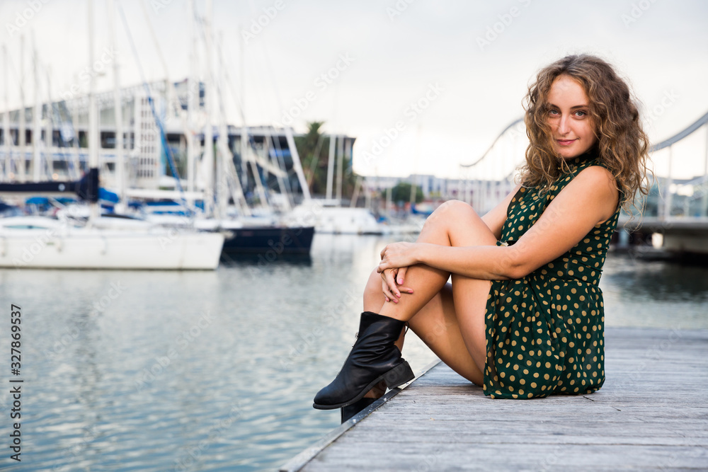 Young attractive woman tourist  sitting at quay  with sailboats on background