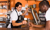 Young man barman giving beer with foam to man client