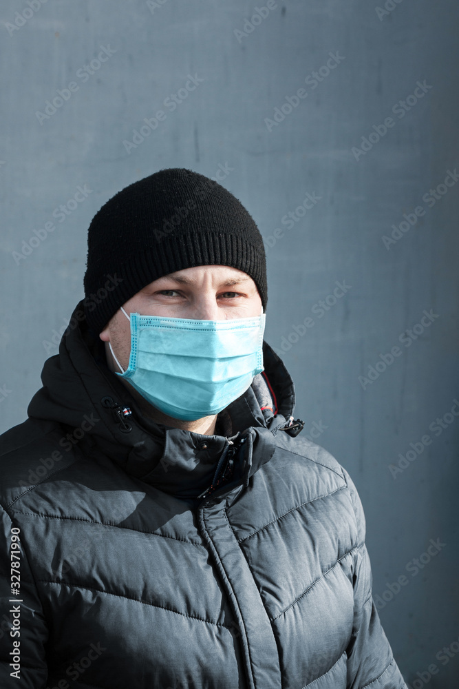 man in blue protective medical mask in the city on a gray background