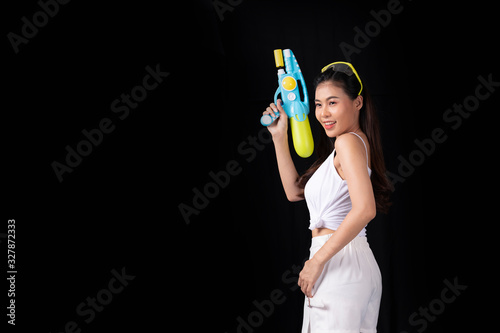 Portrait cheerful young asian woman with red glasses holding plastic water gun on balck background. Songkarn festival, Thailand. Thai New Year's Day. Isolated black background.