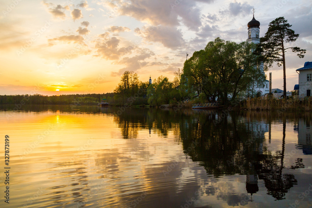 Panoramic view of the Raifa monastery from the lake. Sunset sky. Mirror reflection in the water. Beautiful russian nature. 