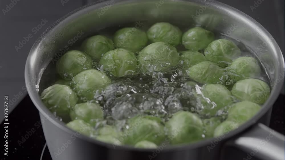 Cook scooping up cooking Brussel Sprouts from a pot of boiling water using a stainless steel draining ladle and then returning them to the water Cook scooping up cooking Brussel Sprouts from a pot of boiling water using a stainless steel draining ladle and then returning them to the water