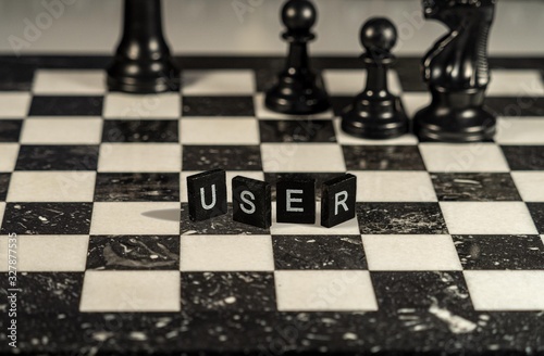 The concept of User represented by black and white letter tiles on a marble chessboard with chess pieces photo