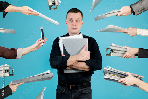 A office employee in a black shirt, hands pull folders, documents towards him