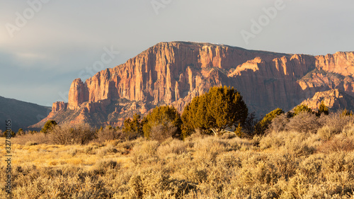 Fotografía A part of Zion National Park known as the Kolob Fingers catches the last rays of a winter day with a field of grass sagebrush and juniper trees in the foreground