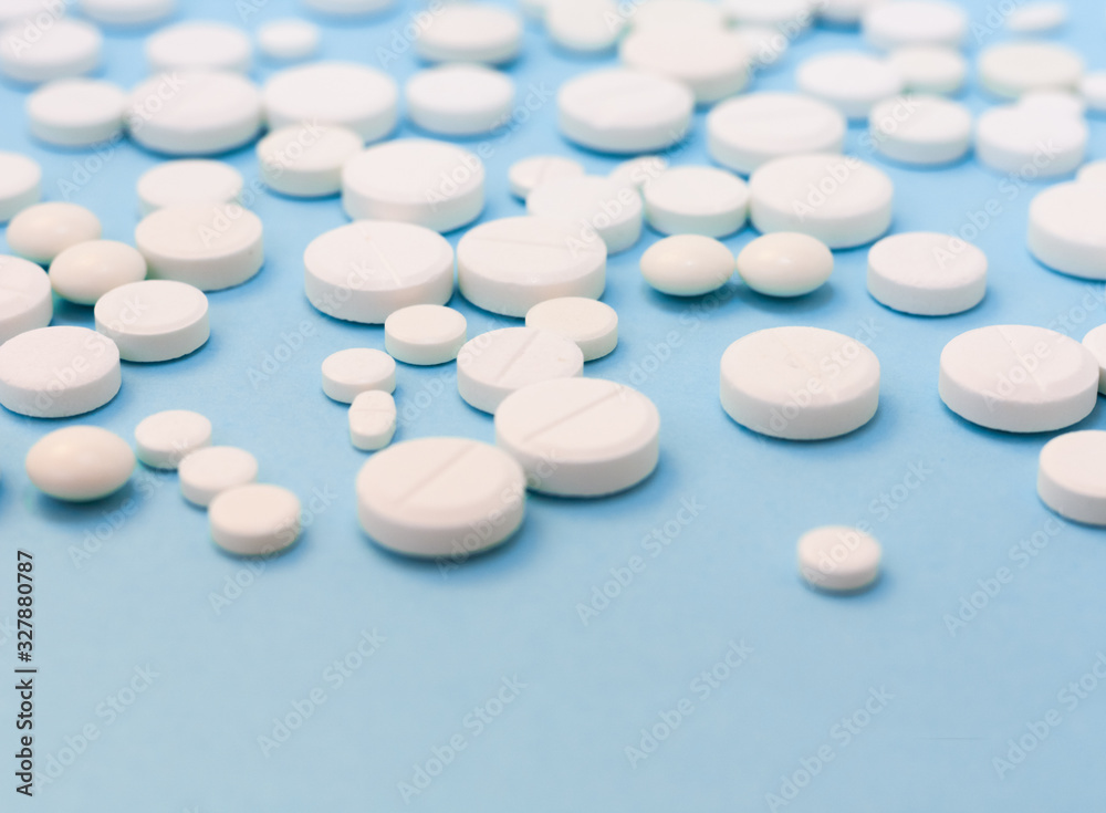 Heap of white pills, tablets, capsules on blue background. Drug prescription for treatment medication health care concept wth copy space. Heap of white pills, tablets, capsules on blue background. Drug prescription for treatment medication health care concept wth copy space.