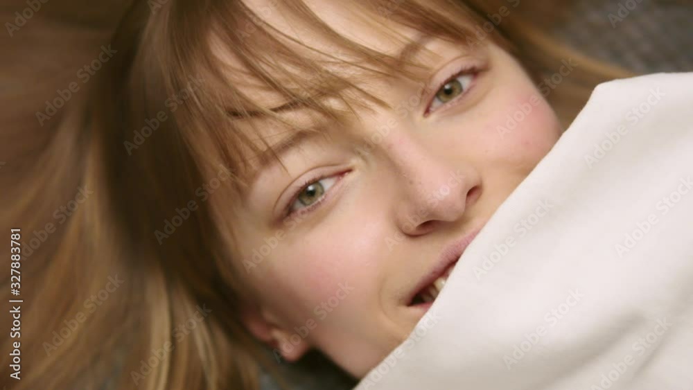 Smiling woman under blanket looking up in her bedroom. Smiling woman under blanket looking up in her bedroom.