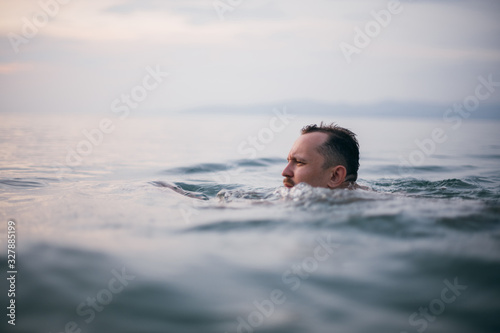 A man swims in the ocean at sunset © Anna