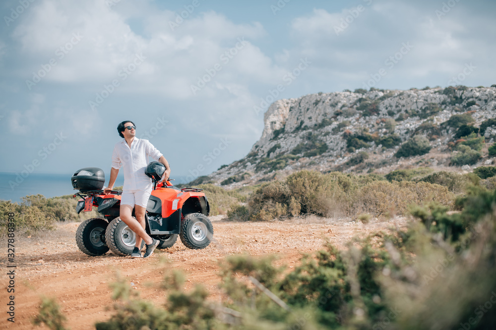 A man with a helmet in his hands next to the ATV A man with a helmet in his hands next to the ATV