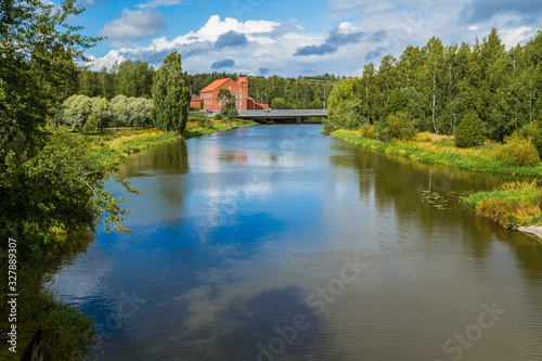 The landscape of the Vantaa river in Vakhakaupunki. Lonely brick house in the distance. Sky reflection in the water.