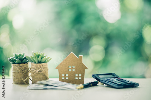 Property investment concept. Wooden house, dollar bill and calculator on table. Pen prepare planning savings money to buy a home, mortgage and real estate investment. photo