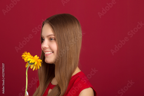 beautiful young woman with a flower in her hands on a red background