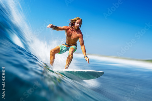 Young man surfer with long hair surfs the fast and perfect ocean wave in Maldives © Dudarev Mikhail