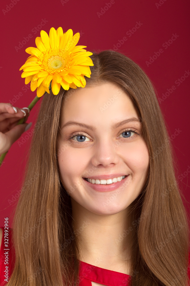 beautiful young woman with a flower in her hands on a red background