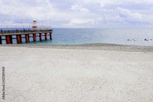 stone, cement foreground with de-focused background consisting of ocean, sea wave and lighthouse. copy space. sky surf summer clouds. Business presentation, product display template , panoramic banner © Любовь Ситникова