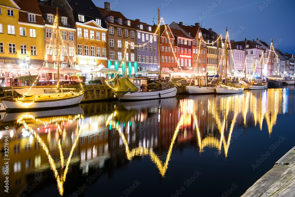 Evening view to boats in front of colourful old houses at Nyhavn harbour canal in Copenhagen, Denmark. February 2020