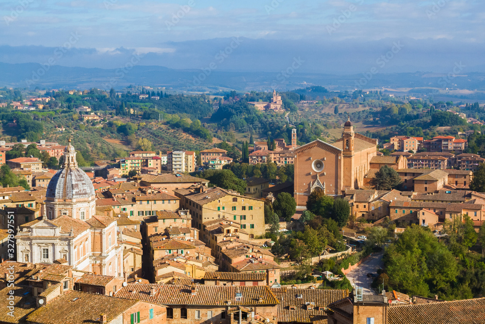 Panoramic view of Siena from The Torre del Mangia. Medieval houses, churches are located on the hillsides, tuscan hills on the horizon. Pictorial cityscape. Tuscany, Italy.