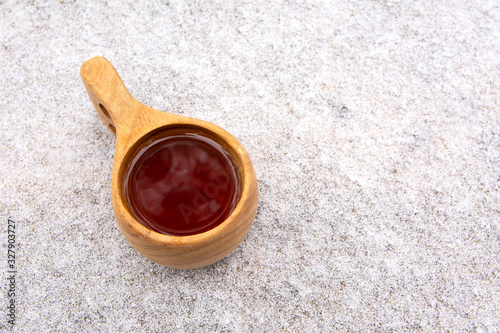 Wooden kuksa with tea on the table covered with snow, Tammela, Finland photo