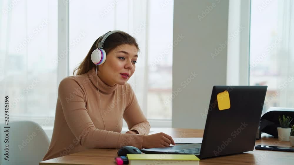 Young business woman in headphones having online meeting on laptop Young business woman in headphones having online meeting on laptop