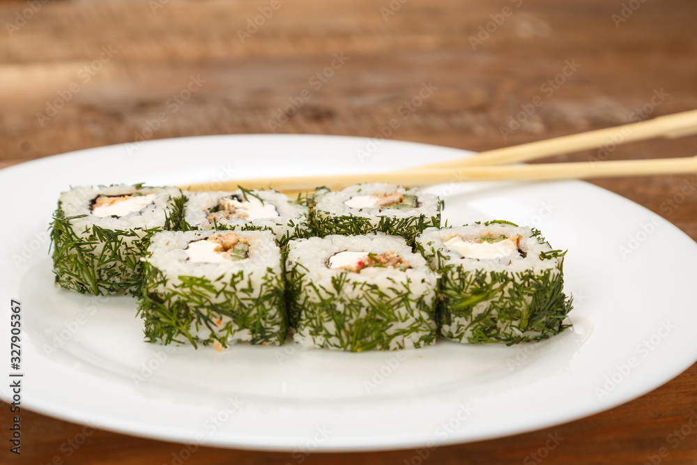 Rolls with salmon and dill on a white plate with chopsticks. Rolls with salmon and dill on a white plate with chopsticks.