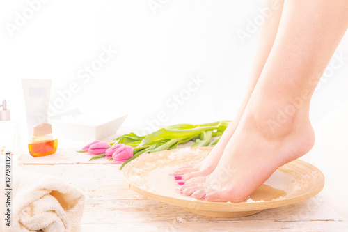 A young woman taking warm footbath with special salts. Home SPA. Woman's Day. photo