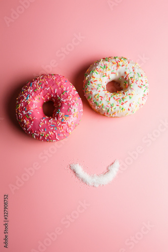 funny smiley of two donuts and sugar on a pink background with place for text, an example of junk food