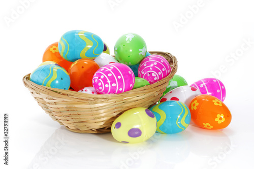 Multi-colored toy easter eggs in a basket on white