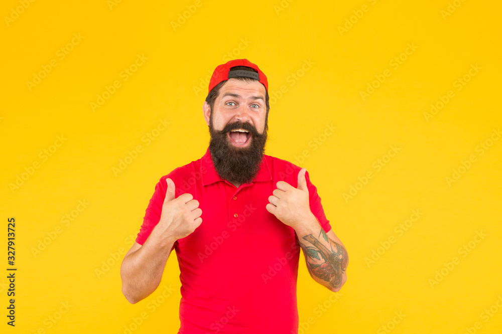 Naklejka premium Hiring shop worker. Hipster cashier. Delivery service. Restaurant cafe staff wanted. Man bearded tattooed hipster wear cap cashier uniform yellow background. Cashier concept. Salesman cashier career