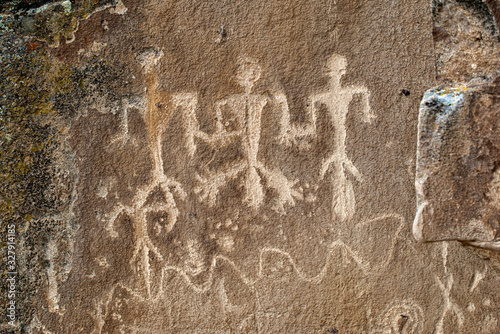 These masculine petroglyphs feature three male anthropomorph body figures each with large phallus. The are above a winding river and surrounded by bear paws.