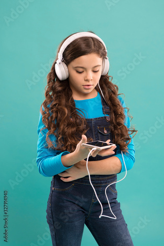 kid listen music in headphones. small child make play list on smartphone. small girl hold mp3 player. choosing favorite song. e-learning in modern life. schoolgirl use new technology