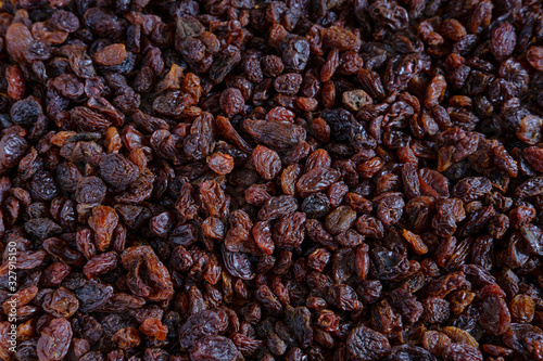 Background of dark, bright and large raisins scattered on the table.