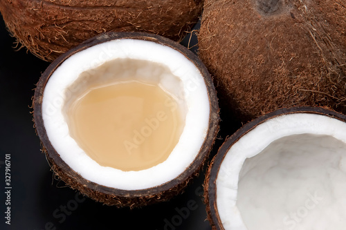cut fresh coconut with real coconut milk on a dark background. vitamin fruits. healthy food