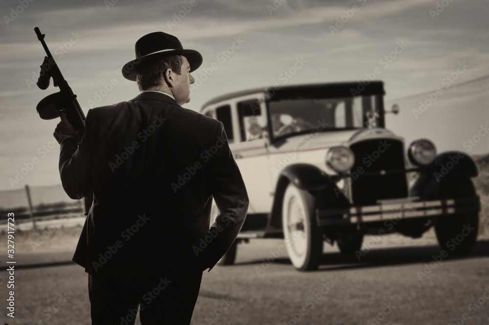 Gangster standing on a road, with a vintage car in the background Stock  Photo | Adobe Stock