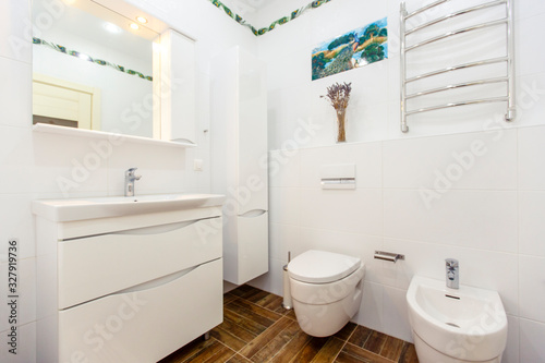 White bathroom in a minimalist style. Bright white tiles  bathroom  toilet  sink  beige tiles on the floor. Stylish  fashionable  minimalistic