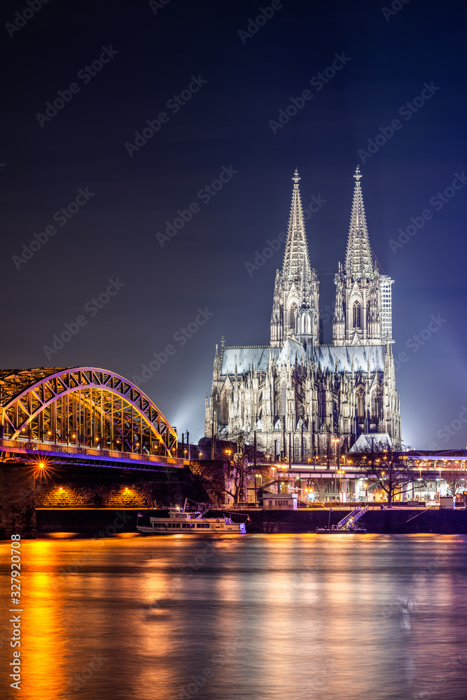 Fototapeta premium Cologne at night with illuminated Cologne Cathedral, Hohenzollern Bridge and Rhine River