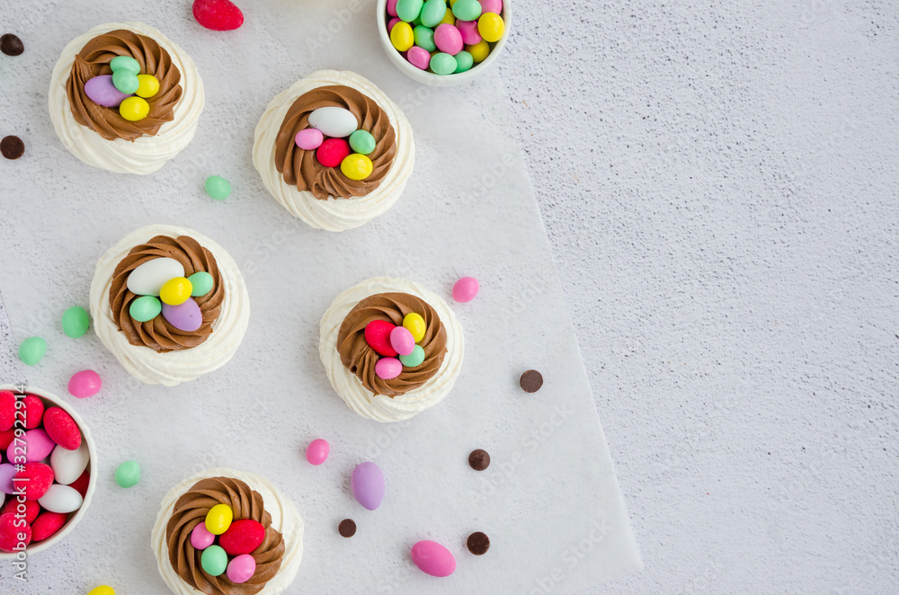 Mini Pavlova Birds Nest with chocolate cream and colored candy. Merengue Cookies. Food idea for kids. Easter cake. Horizontal orientation. Top view. Copy space.
