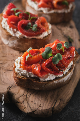 Sandwich with soft cheese and baked red bell pepper on a wooden board.