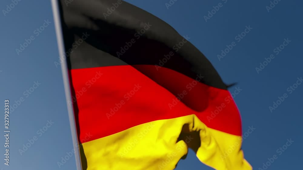 The national flag of Germany flutters in the wind against a blue sky The national flag of Germany flutters in the wind against a blue sky