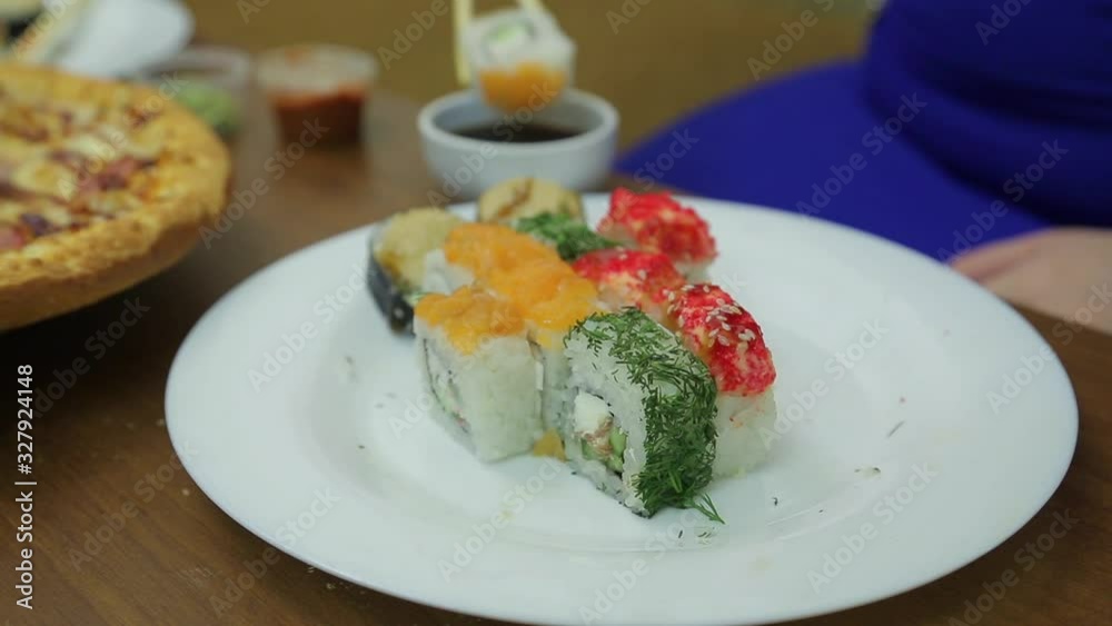 A female hand takes a roll with chopsticks and dips in soy sauce A female hand takes a roll with chopsticks and dips in soy sauce