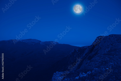 Mesmerizing picturesque mountain landscape with a full moon at night. Concept of pristine nature and the mystic moon. Advertising space
